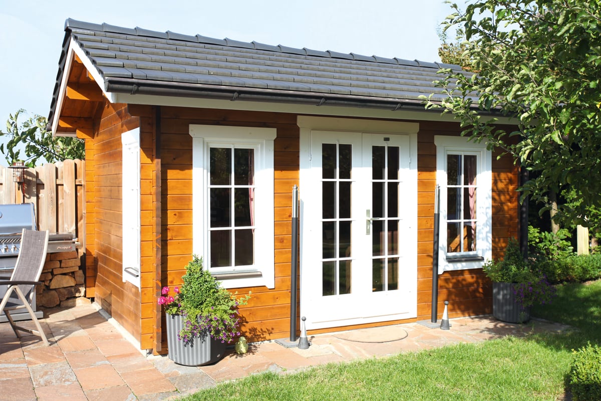 Holzhaus auf Gehwegplatten in einem Garten mit Rasen