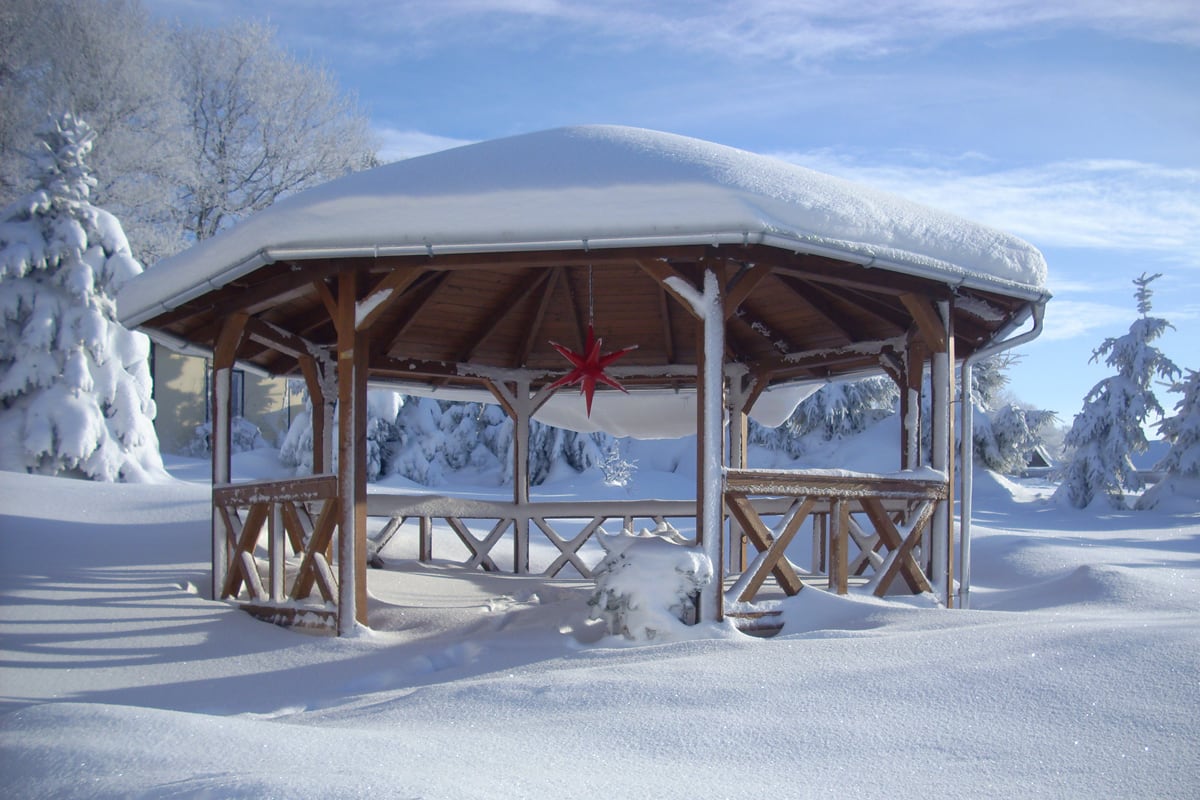 Achteckiger Holzpavillon Lyon in einer Winterlandschaft mit Schnee auf dem Dach.
