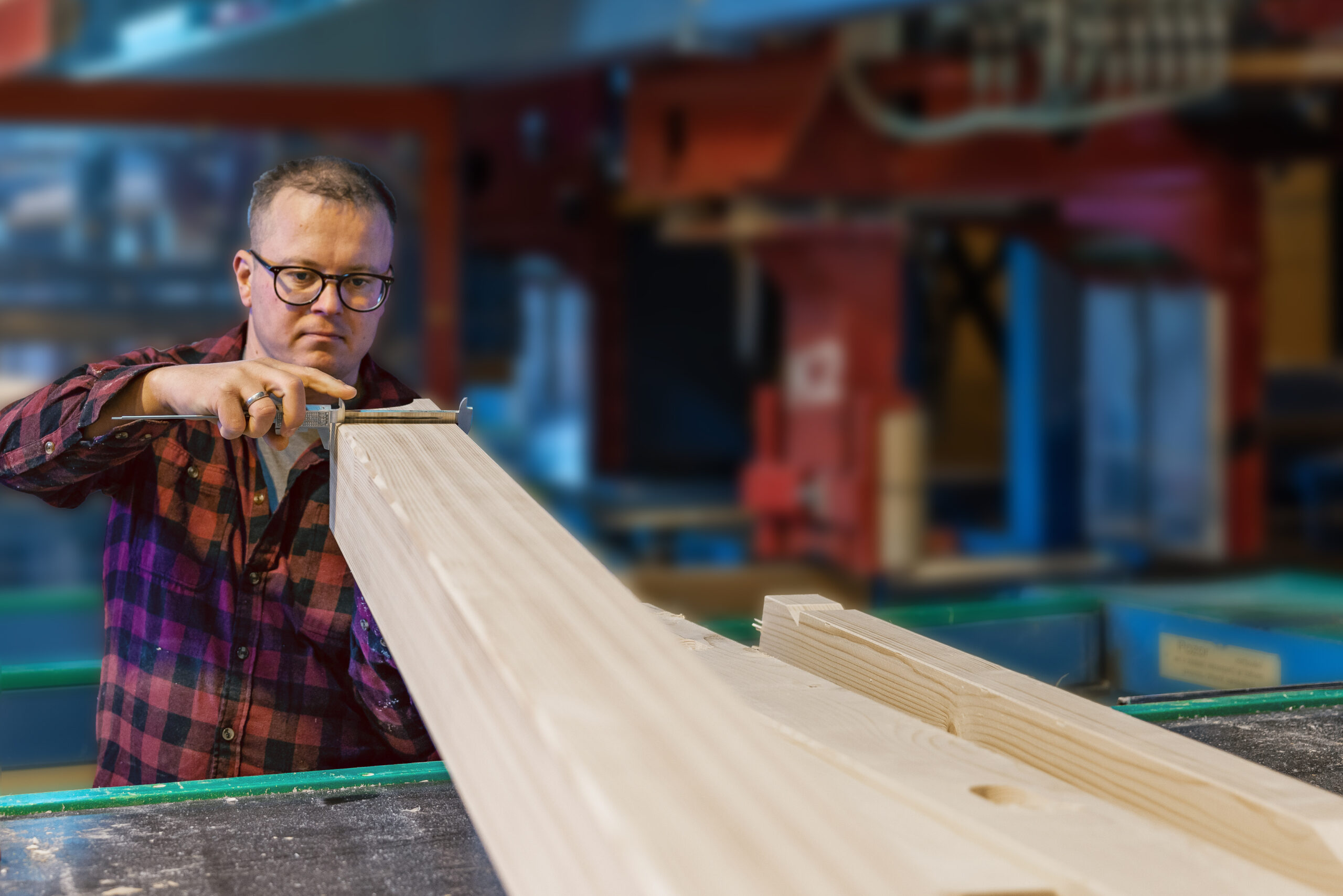 Präzise Holzbearbeitung in der Produktion – ein Mitarbeiter misst sorgfältig ein Werkstück für höchste Qualität und Passgenauigkeit.