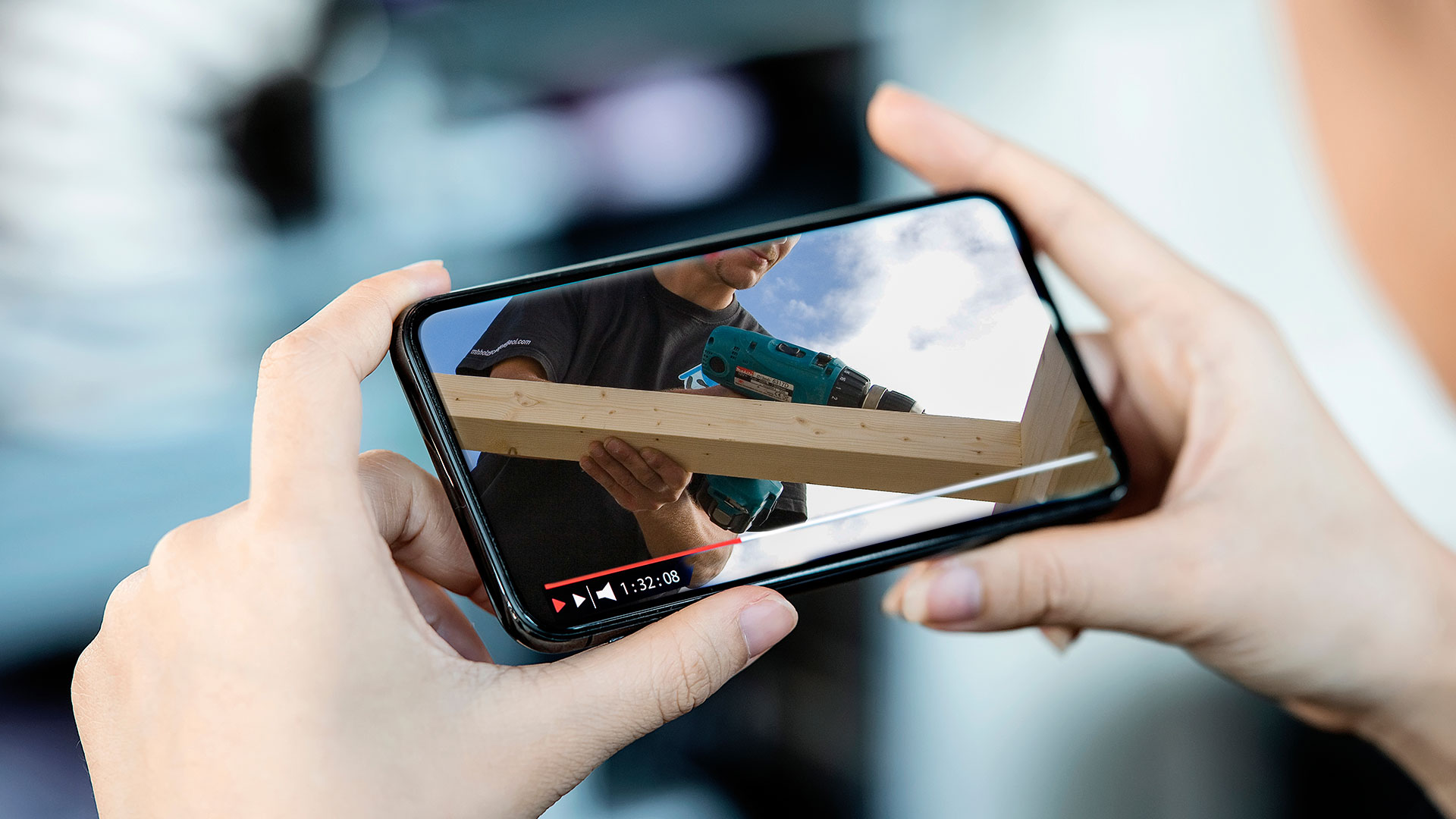 Blick aus ein Handydisplay mit einer arbeitenden Person