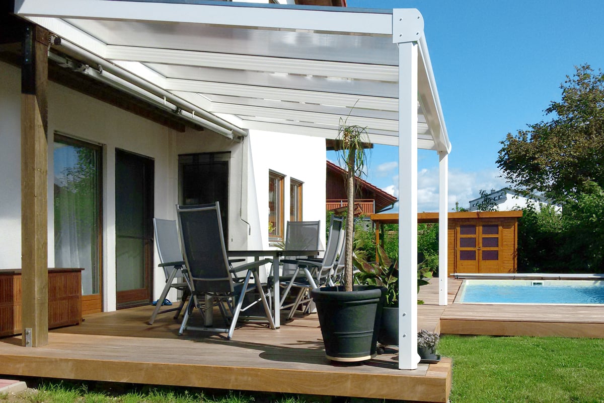 Eine moderne Terrassenüberdachung als Aluminium schafft eine einladende Verbindung zwischen Wohnraum, Garten und Poolbereich.