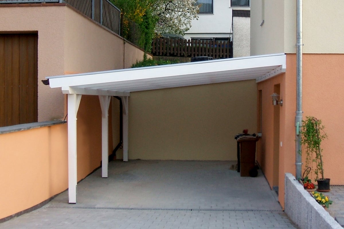 Weißes Carport als Wandanbau in einer Einfahrt