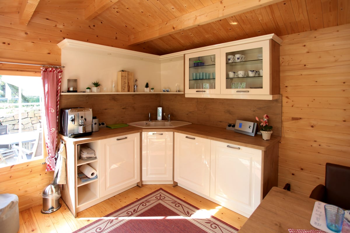 Weiße Küchenzeile in einem Gartenhaus aus Holz
