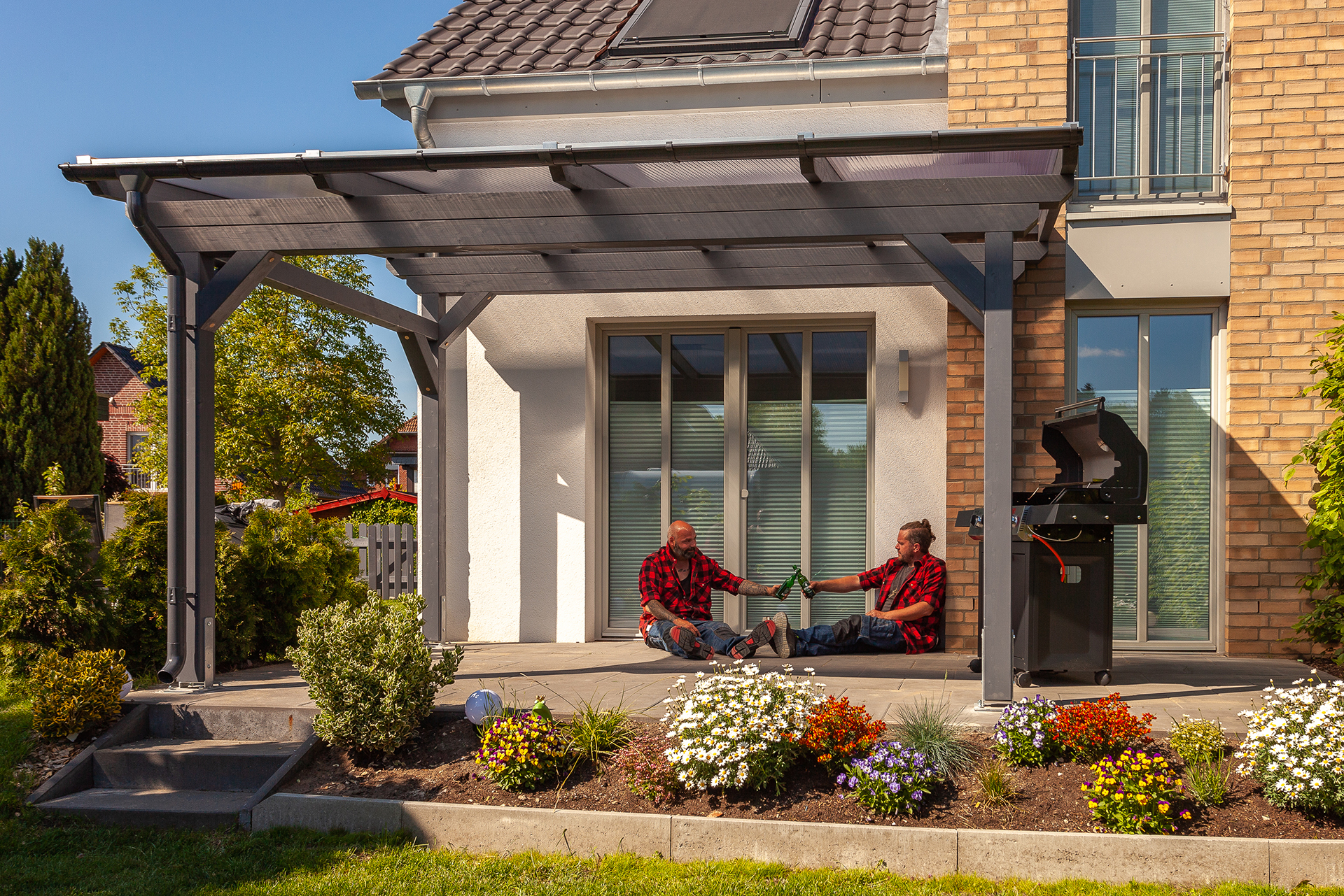 Zwei Heimwerker unter einer Terrassenüberachung mit Feierabendbier