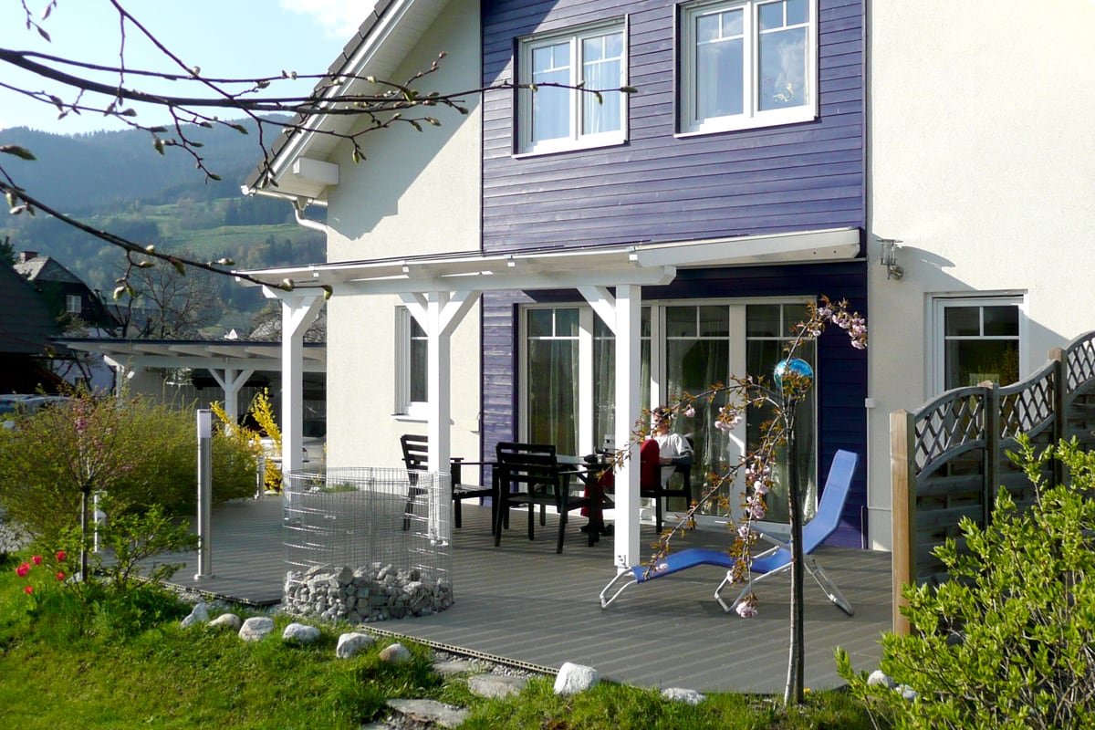 Moderne Terrassenüberdachung die einen harmonischen Übergang zwischen Haus und Garten schafft. Die hochwertige Holzkonstruktion bietet eine langlebige und ästhetische Lösung für geschützte Außenbereiche.