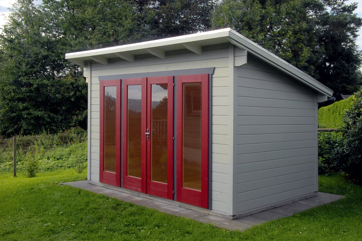 Kleines Gartenhaus Ostende mit grauen Holzplatten und roten Doppeltüren, umgeben von grünem Rasen und Bäumen