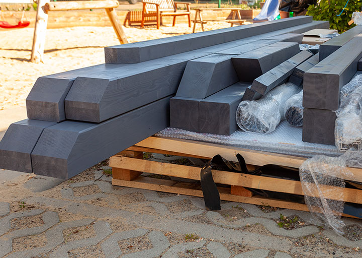 Sauber zugeschnittene, dunkel lasierte Holzbalken – vorbereitet für den Aufbau einer hochwertigen Holz­konstruktion.