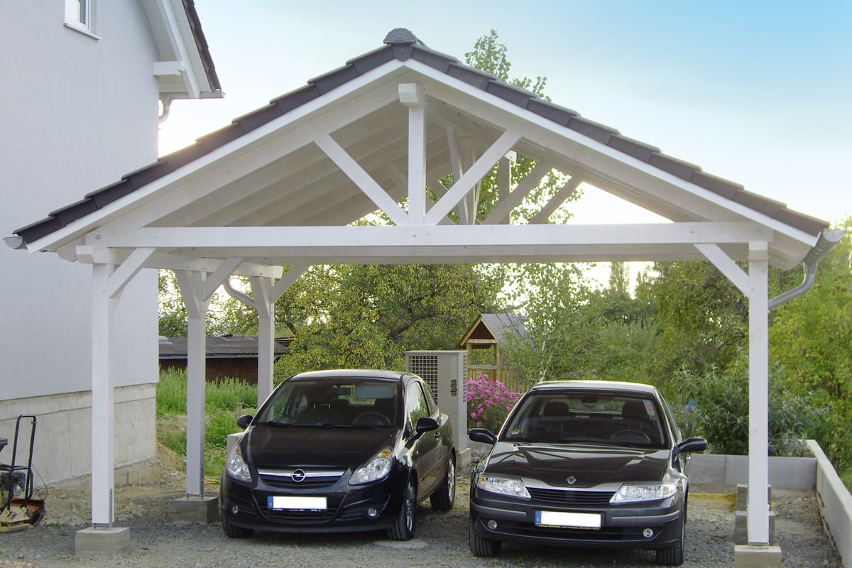 Doppelcarport aus massivem Holz mit Satteldach für optimalen Wetterschutz und eine ansprechende Optik. Die stabile Konstruktion in heller Ausführung fügt sich harmonisch in die Umgebung ein und bietet großzügigen Platz für zwei Fahrzeuge.