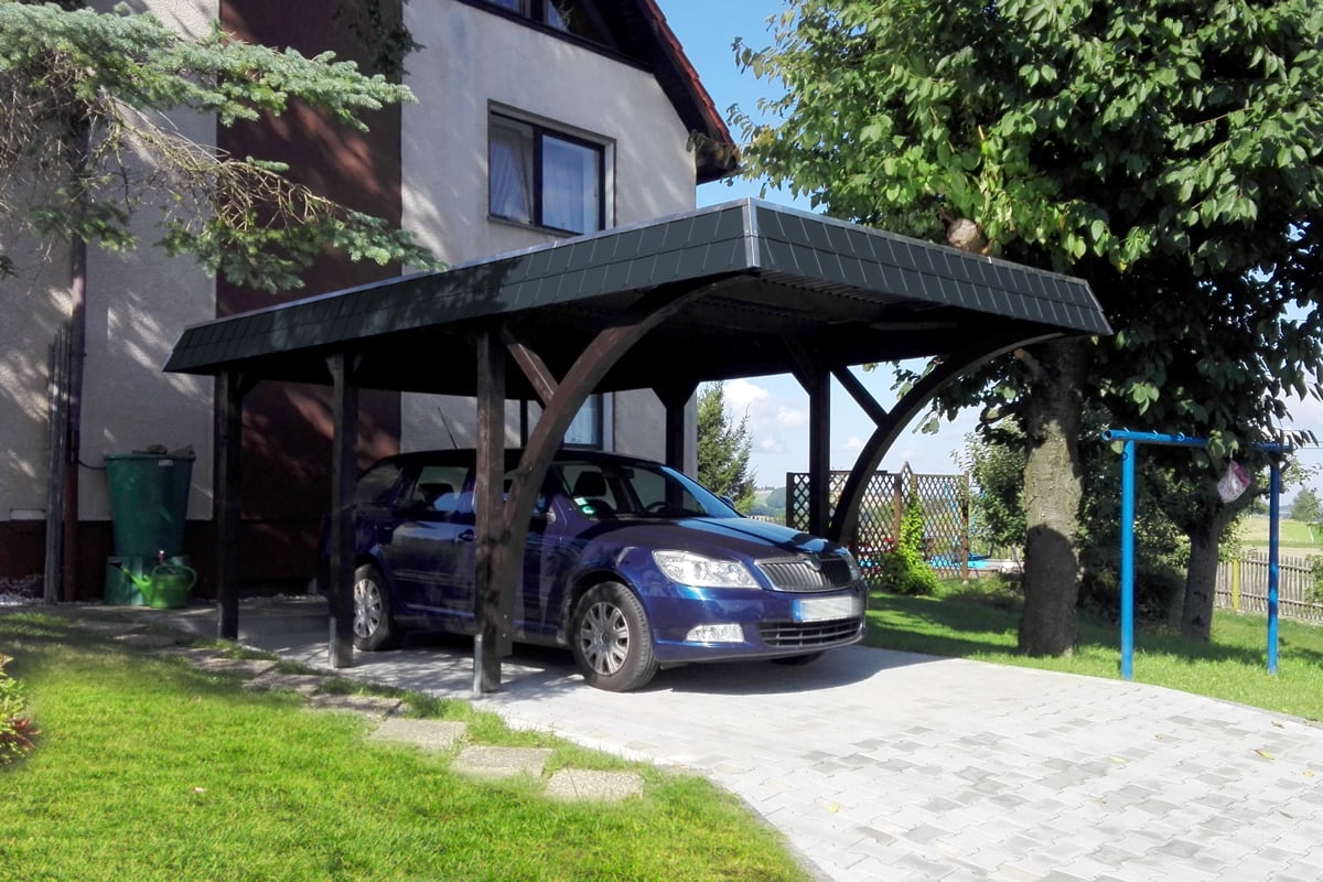 Stilvoller Carport aus dunkel lasiertem Holz mit elegantem Walmdach – langlebiger und witterungsbeständiger Schutz für Ihr Fahrzeug.