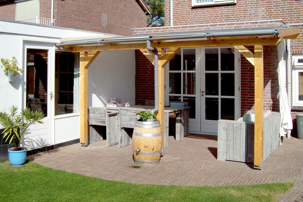 Eine Terrassenüberdachung aus Holz die mit rustikalen Holzmöbeln und einem dekorativen Weinfass ausgestattet ist.