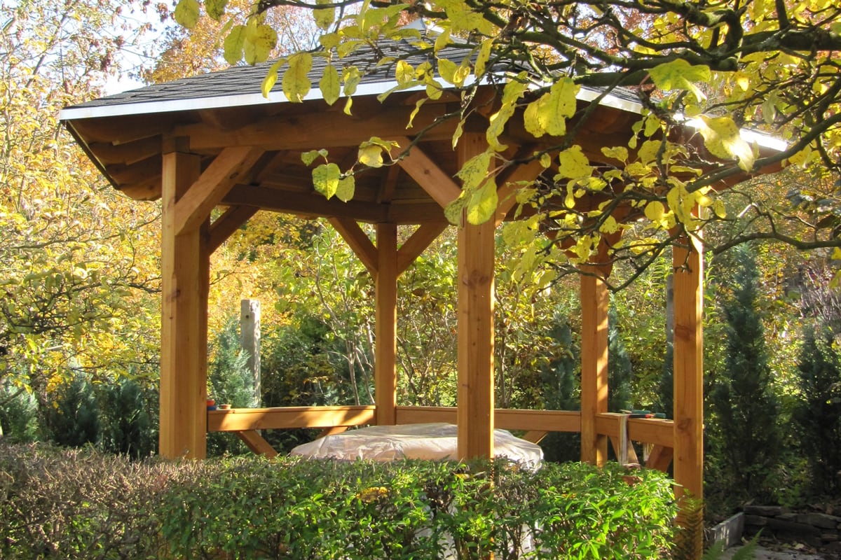 Sechseckiger massiver Holzpavillon Nice hinter einer Hecke