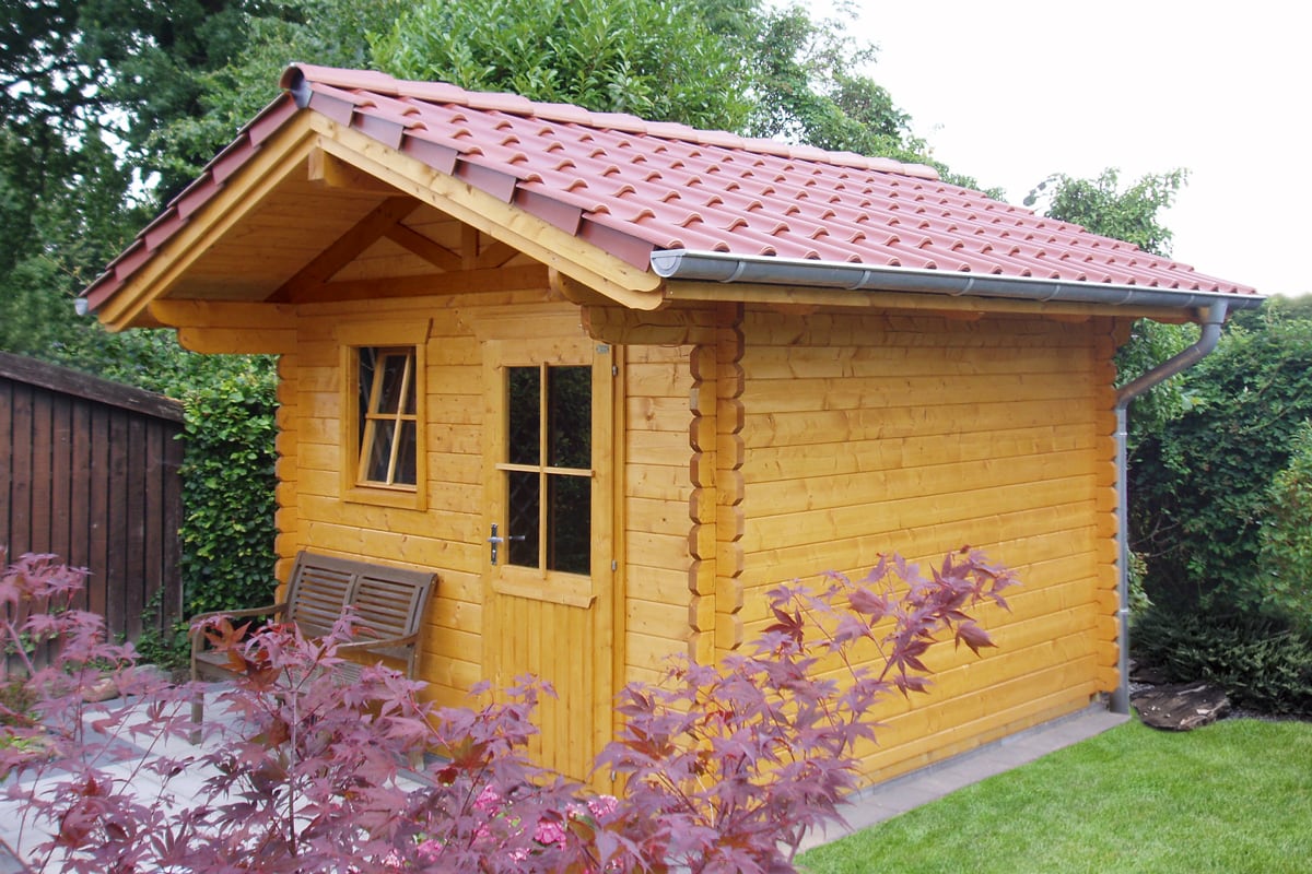 Kleines Gartenhaus Arosa aus Holz mit rotem Ziegeldach, Fenster und Tür mit Glas, umgeben von grünen Pflanzen und Rasen