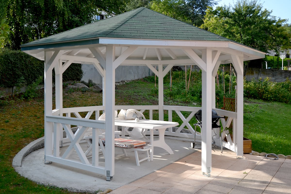 Holzpavillon Nice in weiß mit Brüstungen in einem Garten vor einem Hang